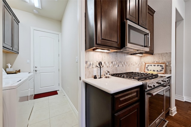 kitchen featuring washing machine and clothes dryer, decorative backsplash, appliances with stainless steel finishes, light tile patterned flooring, and dark brown cabinetry