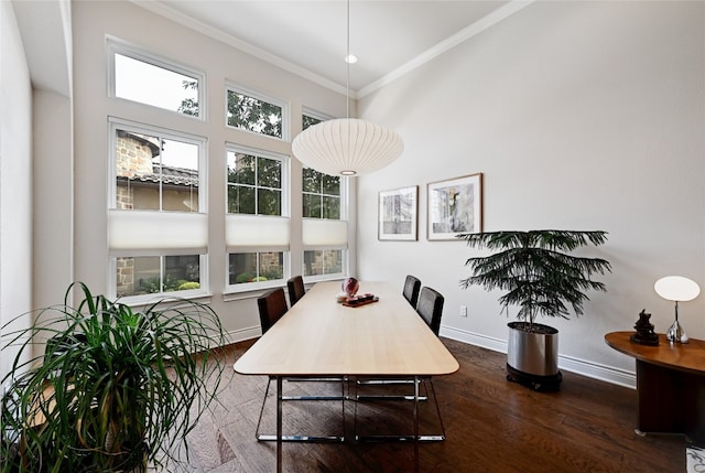 dining space with dark wood-type flooring, a high ceiling, crown molding, and a healthy amount of sunlight