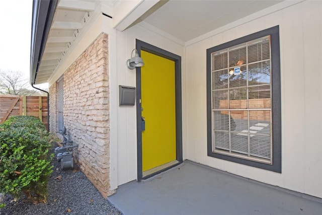 entrance to property featuring stone siding and fence