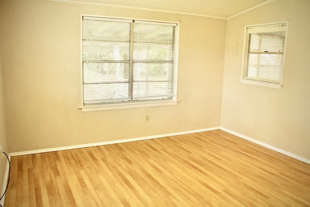 spare room featuring a wealth of natural light, hardwood / wood-style flooring, and ornamental molding