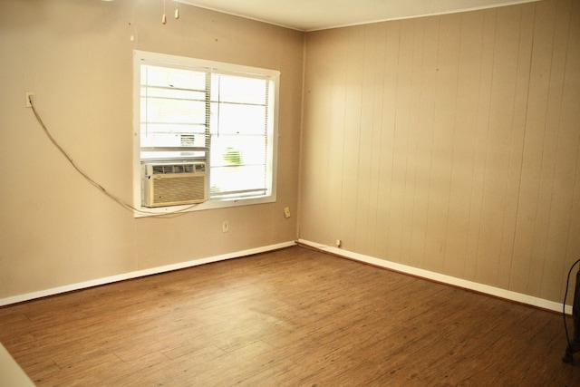 unfurnished room featuring wood walls, wood-type flooring, and cooling unit