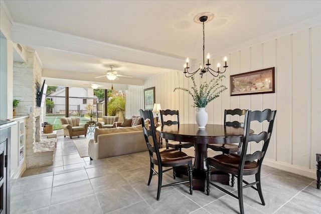 dining space featuring light tile patterned flooring, ornamental molding, ceiling fan with notable chandelier, and a fireplace