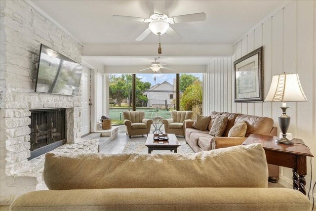 sunroom / solarium featuring ceiling fan and a stone fireplace