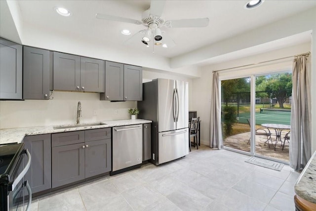 kitchen with sink, gray cabinets, ceiling fan, stainless steel appliances, and light stone countertops