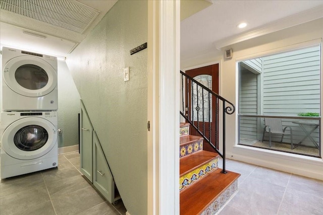 clothes washing area with tile patterned floors and stacked washer / dryer