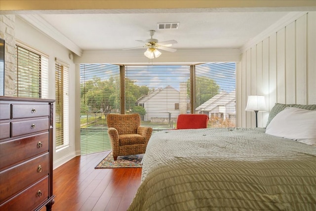 bedroom with dark wood-type flooring, ceiling fan, and ornamental molding