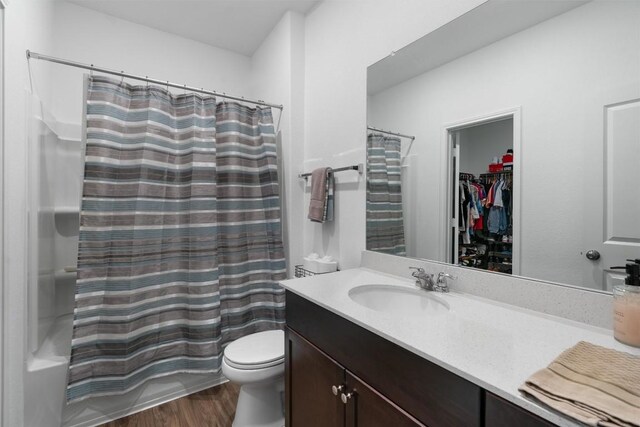 full bathroom featuring hardwood / wood-style floors, vanity, toilet, and shower / bathtub combination with curtain