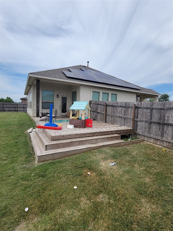 back of house featuring a deck and a lawn