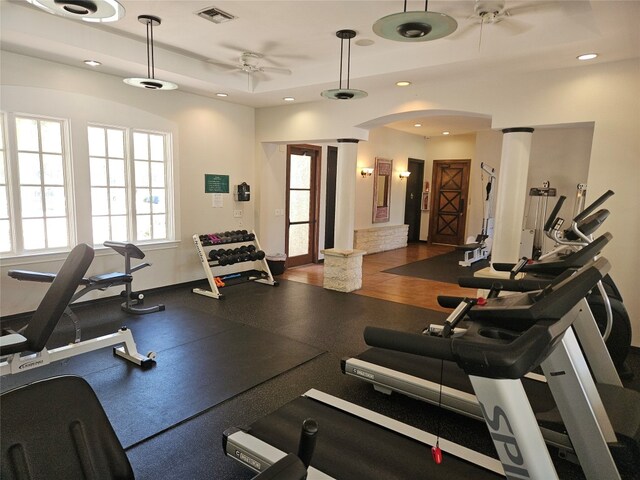 exercise room with ceiling fan, wood-type flooring, and decorative columns