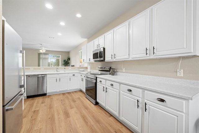 kitchen featuring ceiling fan, kitchen peninsula, appliances with stainless steel finishes, white cabinets, and light wood-type flooring