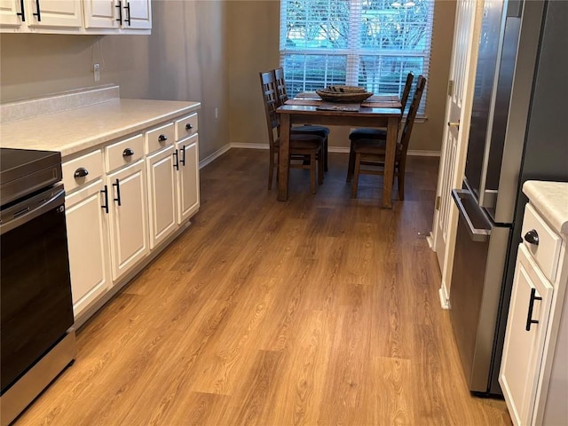 kitchen featuring white cabinets, stainless steel fridge, range, and light hardwood / wood-style flooring