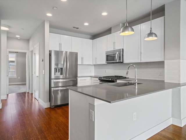 kitchen featuring visible vents, a sink, baseboards, a peninsula, and stainless steel appliances