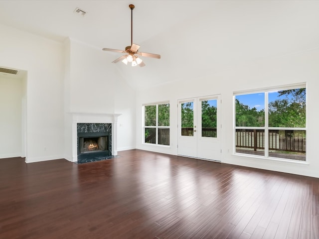 unfurnished living room with a wealth of natural light, dark wood-type flooring, ceiling fan, and a premium fireplace