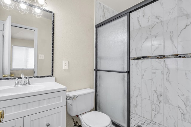 bathroom featuring a shower with shower door, toilet, and vanity