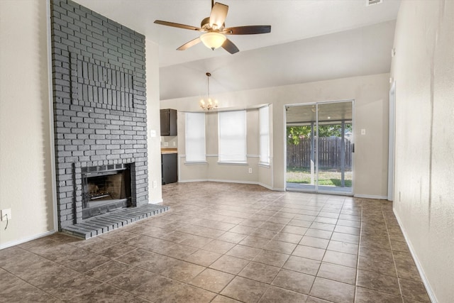 unfurnished living room featuring dark tile patterned floors, ceiling fan with notable chandelier, a brick fireplace, and vaulted ceiling