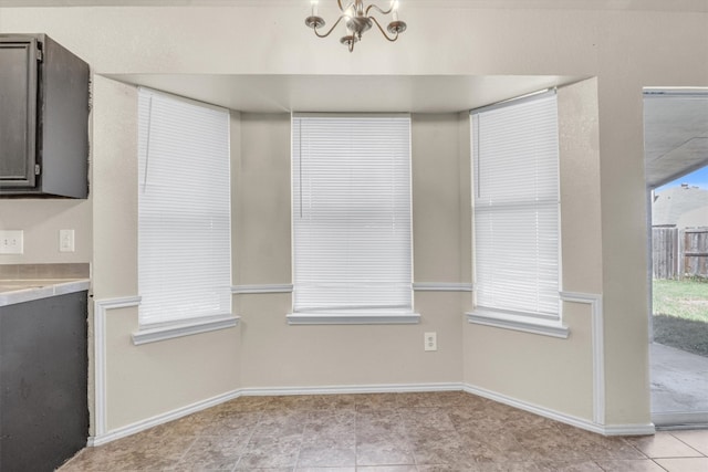 unfurnished dining area featuring light tile patterned floors and an inviting chandelier