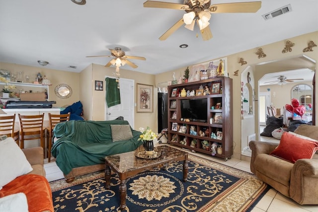 living room featuring tile patterned flooring, visible vents, arched walkways, and a ceiling fan