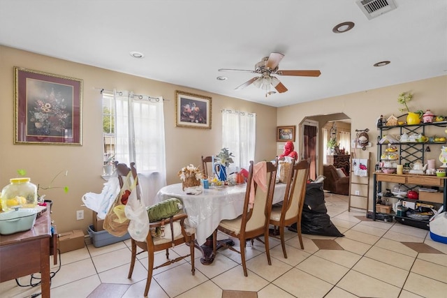 dining space with arched walkways, ceiling fan, light tile patterned floors, and visible vents