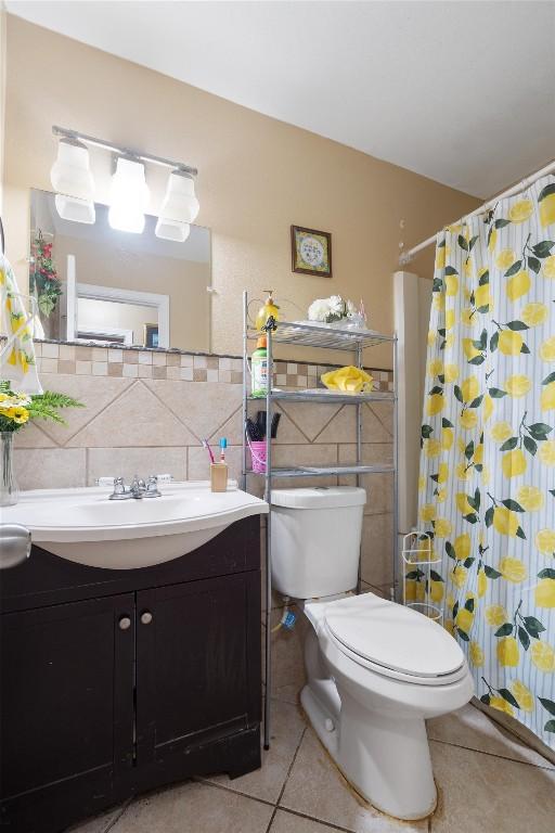 bathroom with a shower with curtain, vanity, toilet, and tile patterned floors