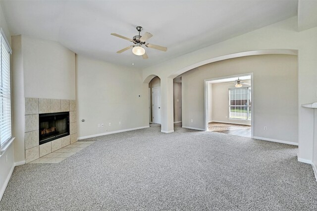 unfurnished living room featuring light carpet, ceiling fan, and a tiled fireplace