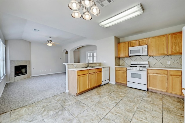 kitchen with white appliances, ceiling fan with notable chandelier, sink, a fireplace, and light colored carpet