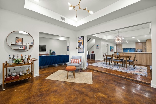 living room featuring a tray ceiling and a chandelier