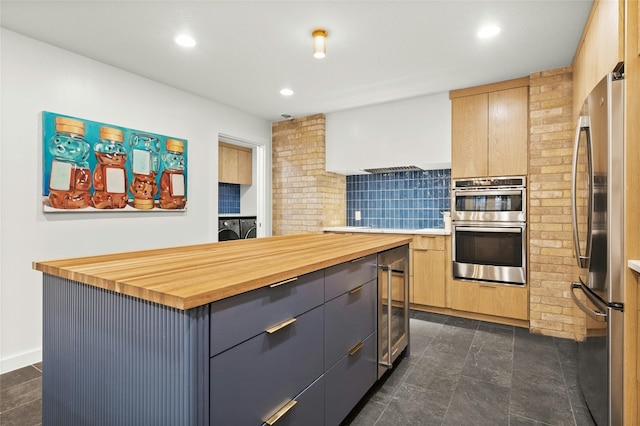 kitchen featuring light brown cabinetry, butcher block counters, a center island, appliances with stainless steel finishes, and gray cabinets