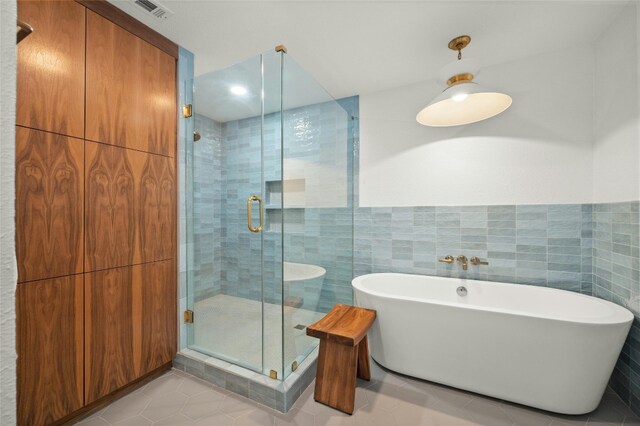 bathroom featuring tile patterned flooring, shower with separate bathtub, and tile walls