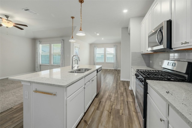 kitchen featuring visible vents, a sink, backsplash, light wood-style floors, and appliances with stainless steel finishes