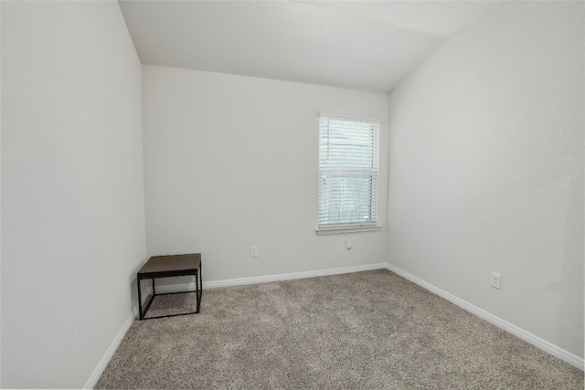 spare room featuring baseboards, carpet flooring, and vaulted ceiling