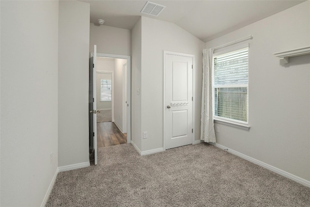 unfurnished bedroom with lofted ceiling, baseboards, visible vents, and carpet floors