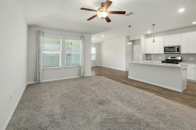 kitchen with visible vents, backsplash, open floor plan, appliances with stainless steel finishes, and white cabinets