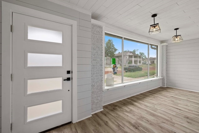 foyer featuring a healthy amount of sunlight, wood walls, and wood-type flooring