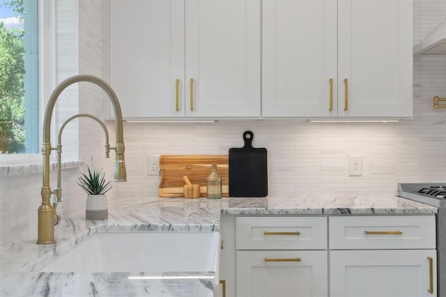 kitchen featuring light stone counters, white range oven, and white cabinets