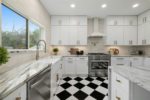 kitchen with white cabinetry, wall chimney range hood, tasteful backsplash, and stainless steel appliances