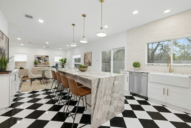 kitchen with pendant lighting, sink, white cabinetry, a kitchen island, and stainless steel dishwasher