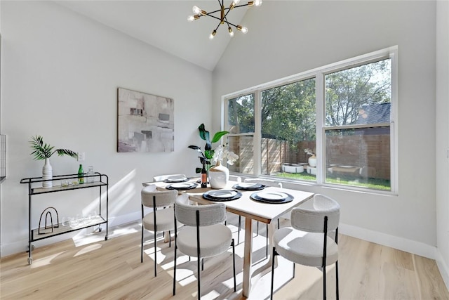 dining room with light wood-type flooring, high vaulted ceiling, and an inviting chandelier