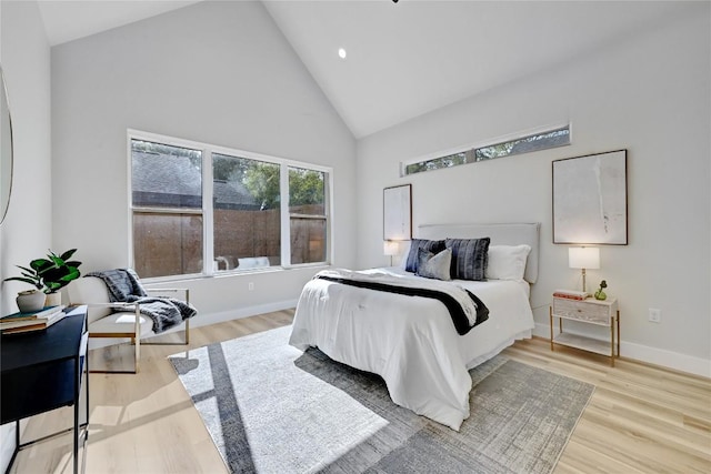 bedroom with light hardwood / wood-style floors and high vaulted ceiling