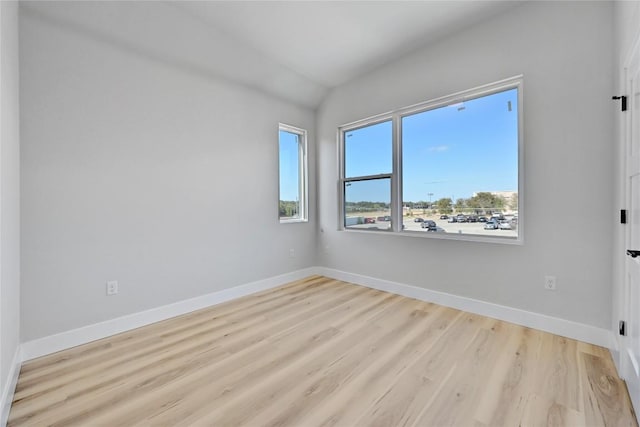 empty room featuring light hardwood / wood-style flooring and vaulted ceiling