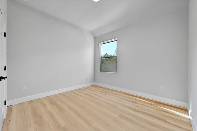 empty room with light wood-type flooring and vaulted ceiling