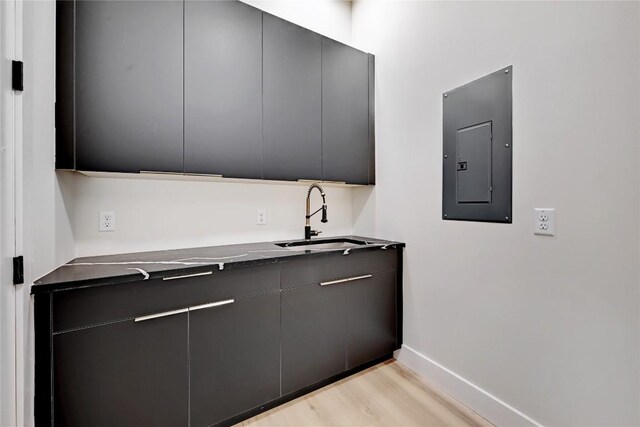 kitchen with gray cabinetry, light hardwood / wood-style floors, sink, and electric panel