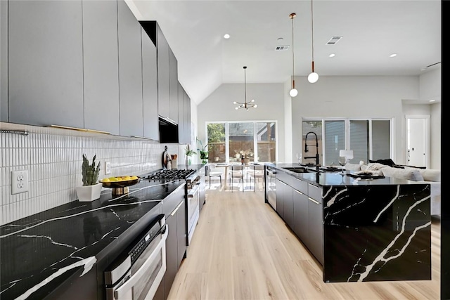 kitchen with sink, stainless steel appliances, hanging light fixtures, an inviting chandelier, and tasteful backsplash