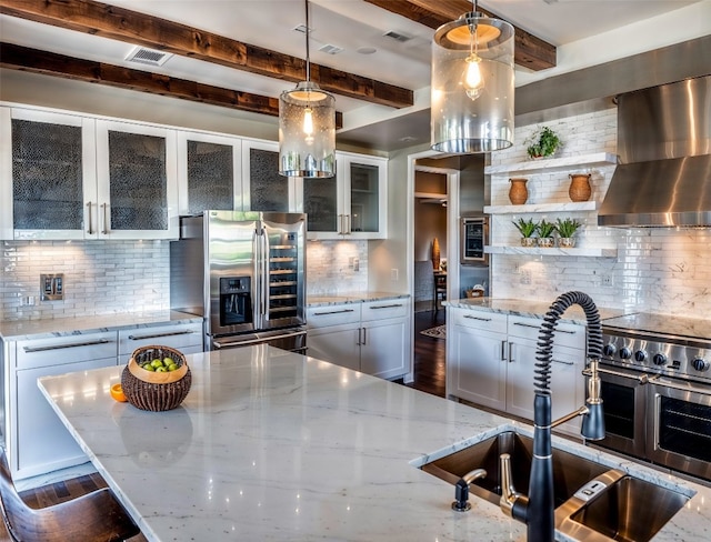 kitchen with hanging light fixtures, sink, light stone countertops, decorative backsplash, and stainless steel refrigerator with ice dispenser