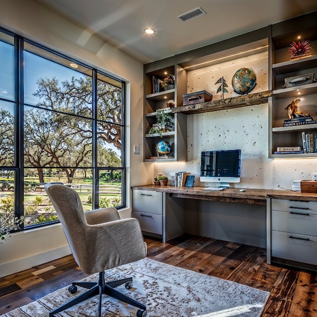 home office featuring built in desk and dark hardwood / wood-style floors