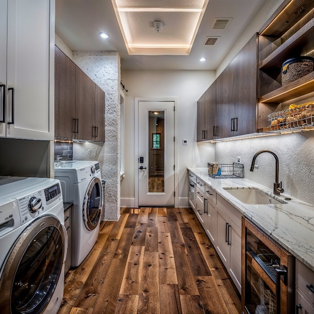 washroom with dark hardwood / wood-style floors, washing machine and clothes dryer, cabinets, and sink