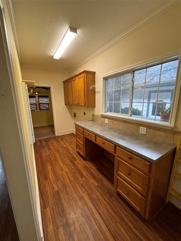 510 S Church St, Georgetown, TX 78626 - kitchen with built in study area, brown cabinetry, dark wood-style floors, and crown molding
