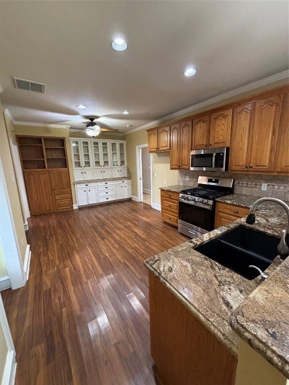 510 S Church St, Georgetown, TX 78626 - kitchen with appliances with stainless steel finishes, stone countertops, ceiling fan, brown cabinets, and crown molding