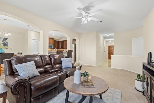 carpeted living room featuring ceiling fan with notable chandelier and sink