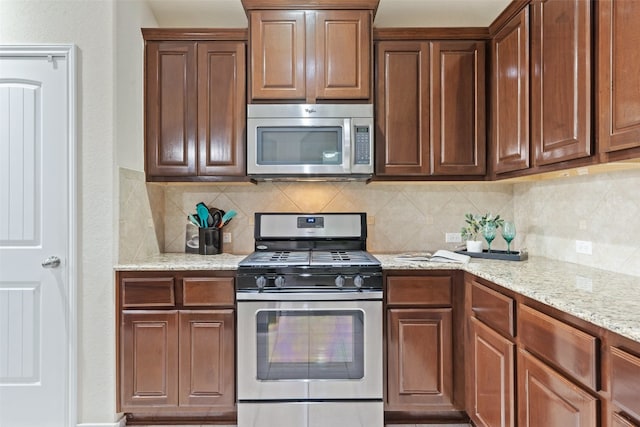 kitchen featuring light stone counters, stainless steel appliances, and tasteful backsplash