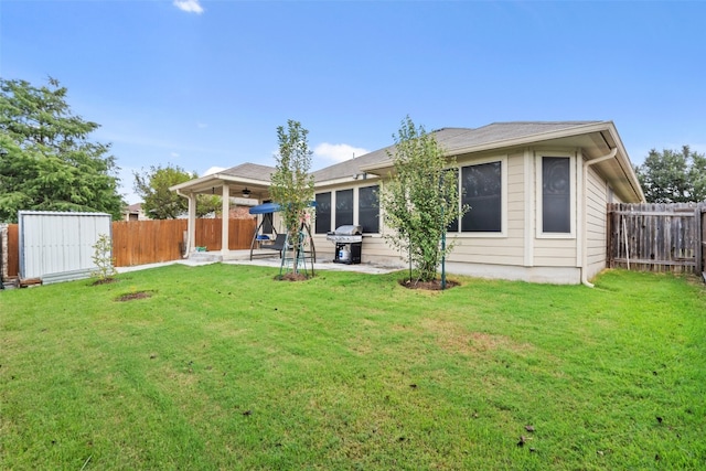 rear view of property featuring a yard, a patio, and a storage shed